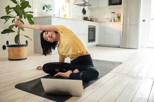 Woman practicing yoga with laptop online class at home
