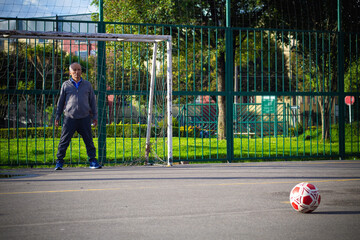 Retired older man being a goalkeeper on a soccer field in a park