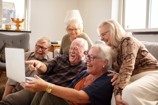 Group of senior people laughing at laptop from home