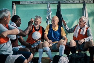 Senior men laughing in locker room before football game - obrazy, fototapety, plakaty