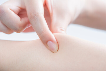 皮膚を強く摘む女性の指先