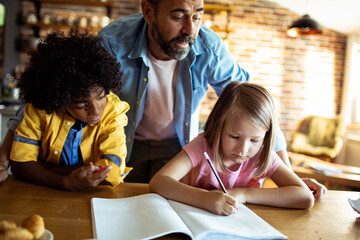 Father helping his diverse children with homework at home