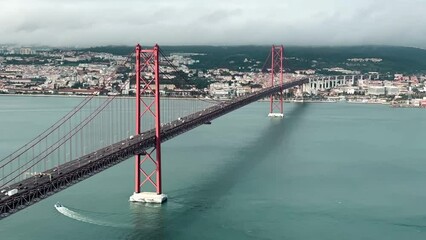A stunning time-lapse of aerial view of the 25 de Abril Bridge in Lisbon, Portugal, spanning the Tagus River with cityscape and traffic. Lisbon, Portugal, 16th of December 2023