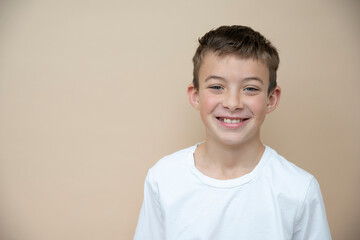 cool 11 years old boy with white t-shirt  in front of brown background in the studio