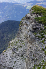 Shot from above of a cliff with lush forest on a background