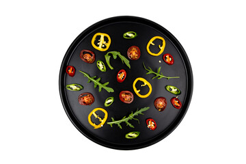 Pattern of chopped vegetables on black plate isolated on white top view