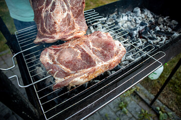 Juicy seasoned meat steaks on a grill grate over burning coals close-up