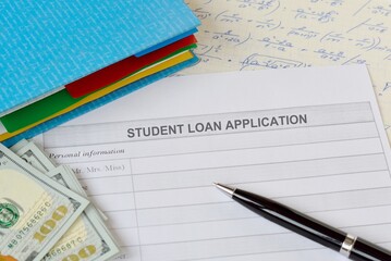  Student loan application form on table with pen, notebook, books and dollar bills. Student education loan concept