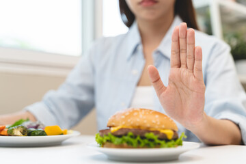Woman on dieting for good health concept. Woman doing cross arms sign to refuse junk food or fast food hamburger that have many fat. - obrazy, fototapety, plakaty