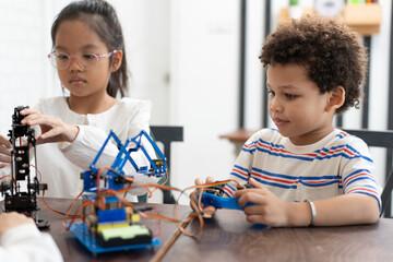 Happy African American kid boy studying with electric robot and friend in classroom
