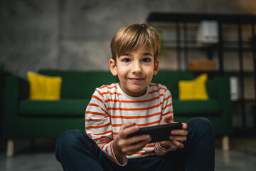 One boy sit at home hold mobile phone smartphone play video games