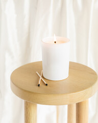 White candle on side table burning, Silk fabric background