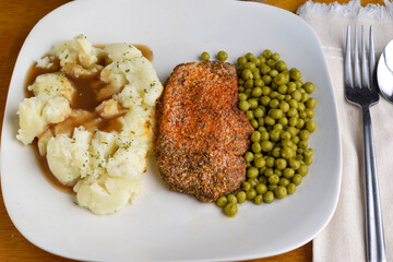 seasoned pork chop  served with mash potatoes and peas