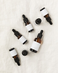 Flay lay of amber glass dropper bottles on linen background