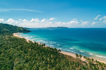 Aerial view of tropical sandy beach in bay with blue water. Seascape with sea, sand, palm trees. Top view of paradise island.