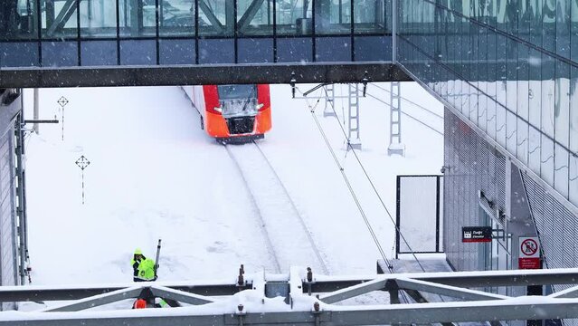 Passenger train arrives at the station during snowfall in winter