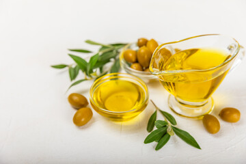 Olive oil in a bottle on a white texture background. Oil bottle with branches and fruits of olives. Place for text. copy space. cooking oil and salad dressing.