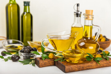 Olive oil in a bottle on a white texture background. Oil bottle with branches and fruits of olives. Place for text. copy space. cooking oil and salad dressing.
