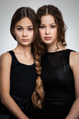 Portrait of two beautiful serious sisters with long hair made in one braid