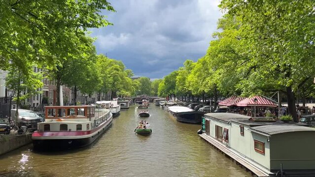 Boat traffic on a typical canal with houseboats in Amsterdam, Netherlands