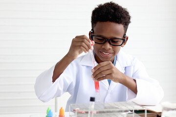 Happy smiling African boy in lab coat holding a test tube for doing science experiments, young...
