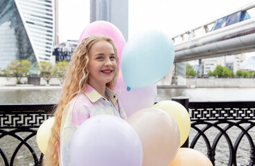 girl with long blond hair walks in the city with balloons in her hands. back to school and holiday