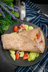 Wholegrain tortilla wraps with vegetables and chicken on a plate.