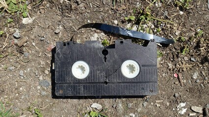 An old broken video cassette abandoned on the ground, testimony to a time gone by.