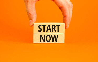 Start now symbol. Concept words Start now on beautiful wooden block. Beautiful orange table orange...