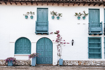 Fachada de casa colonial de puertas azules con flores y enredaderas
