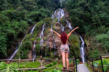 mujer de cabello rojo frente a cascadas sobre la montaña
