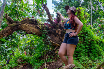 mujer con sombrero junto a árbol caído reverdecido
