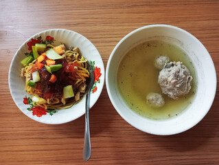 Two bowls of meatballs noodles, top view delicious Indonesian street food on wooden surface table. 