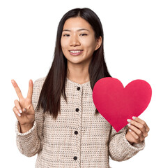 Chinese woman holding Valentine's heart showing number two with fingers.