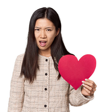 Chinese woman holding Valentine's heart screaming very angry and aggressive.