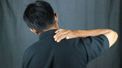 Close-up rear view of man's hand touching shoulder pain, shoulder pain concept.