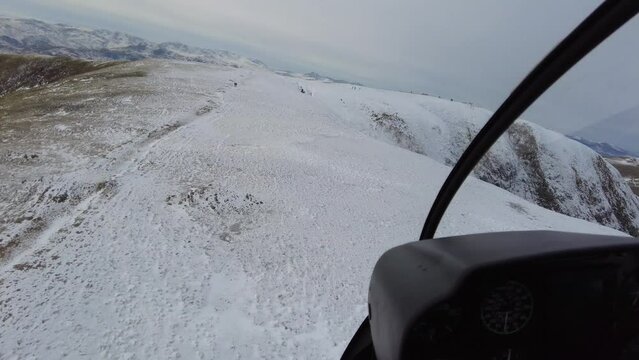 Low altitude high speed mountain top flypast helicopter inside cockpit view people walking hiking skiing winter cold frozen snow
