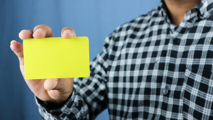 close up attractive business man holding blank yellow mock up card in hand.