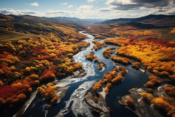 A majestic river flows through a vibrant valley, framed by a stunning backdrop of clouds and mountains, as the rich hues of autumn trees adorn the natural landscape