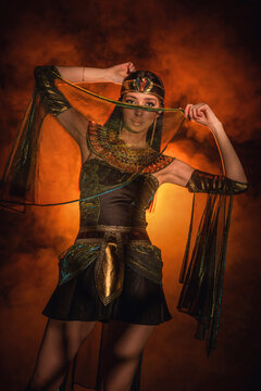 Princess of ancient Egypt girl concept. Young woman posing in the dark on orange smoke background.