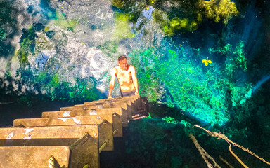 Tourist guide blue turquoise water limestone cave sinkhole cenote Mexico.