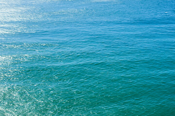 Vivid blue waters cascade softly, merging seamlessly with the sky's azure expanse. The tranquil...
