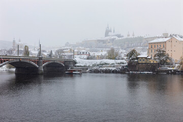 Snowy foggy Prague Lesser Town with gothic Castle above River Vltava, it's snowing, Czech republic
