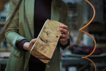 A craftsperson examines a uniquely textured piece of burl wood, appreciating its complex patterns...