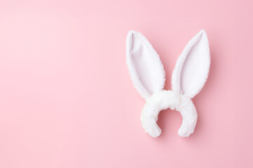 White rabbit ears headband on a light pink background with copy space. Easter concept
