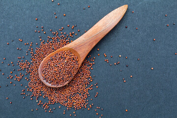 Organic Finger millet or Eleusine coracana seeds in a wooden spoon top view 