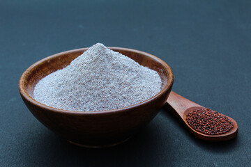 Organic Finger millet or Eleusine coracana powder in a wooden bowl on black background 