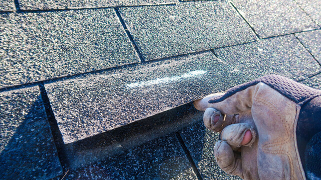 Residential roof inspection for an insurance claim due to storm damage. The asphalt shingles show signs of damage. 