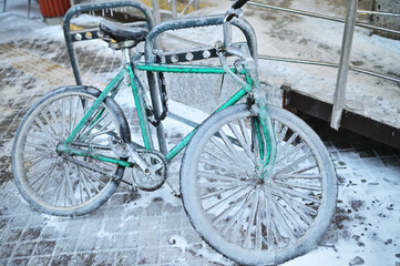 Fototapeta na wymiar green retro bike in ice on a background of snow in winter in a severe frost.