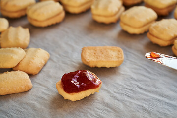 Filling traditional Christmas cookies with strawberry jam - preparation of homemade pastry